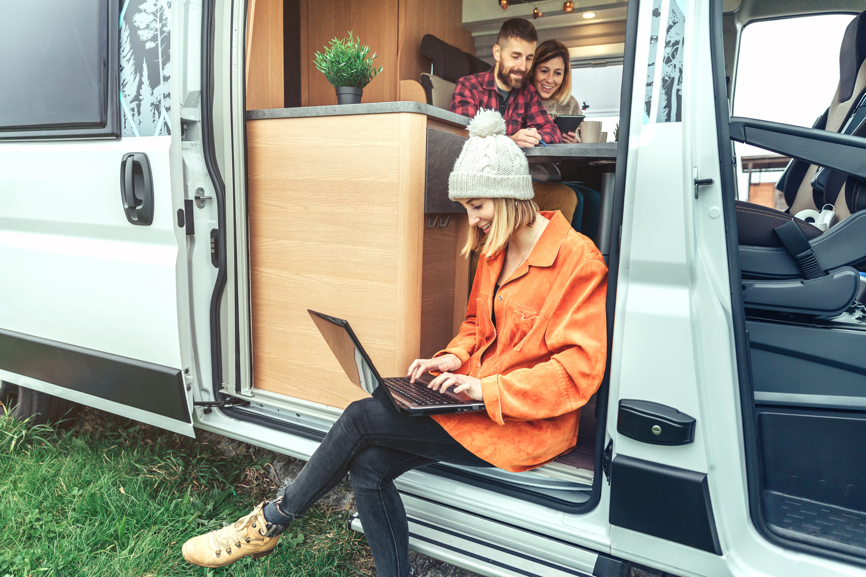 Woman teleworking sitting in the door of a camper van